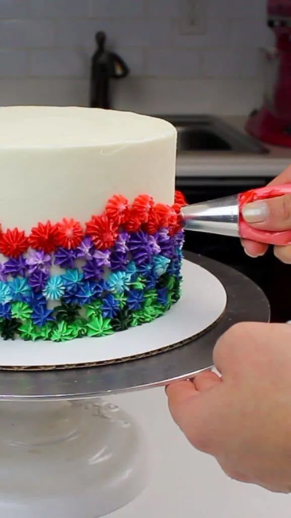 Piping rainbow frosting onto my vanilla cake!