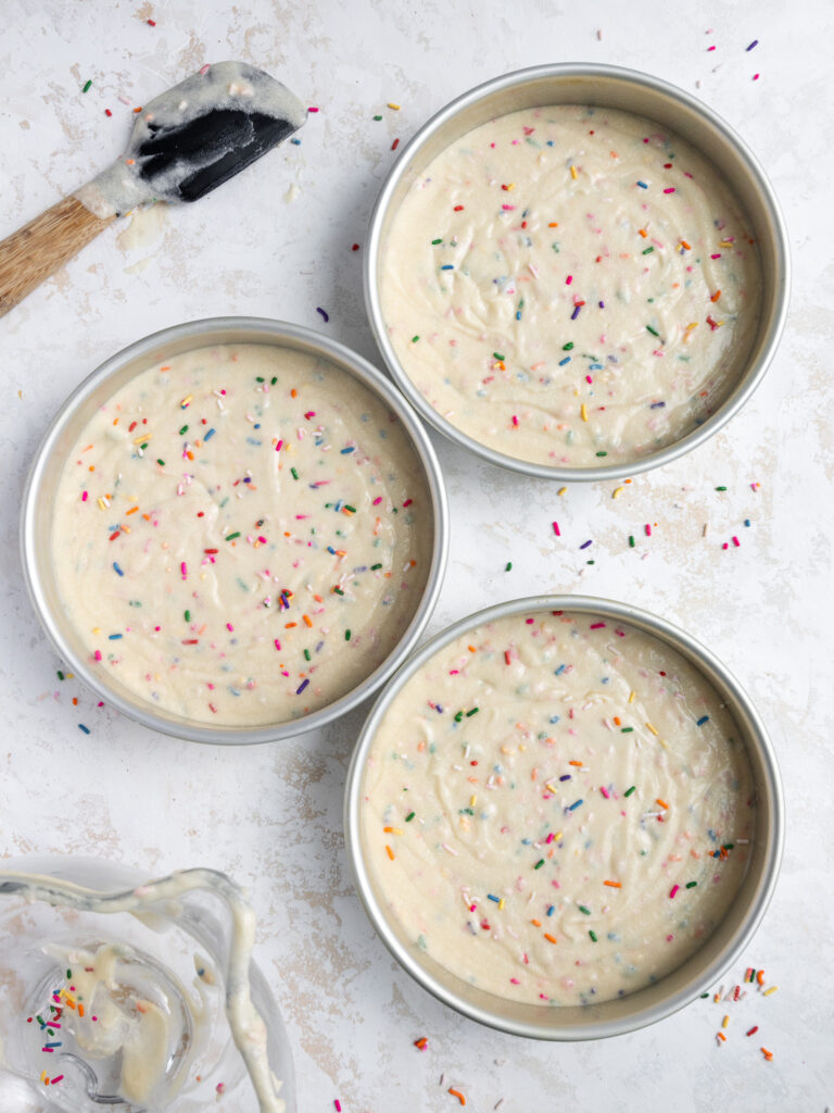 image of funfetti cake batter that's been poured into cake pans and is ready to be baked