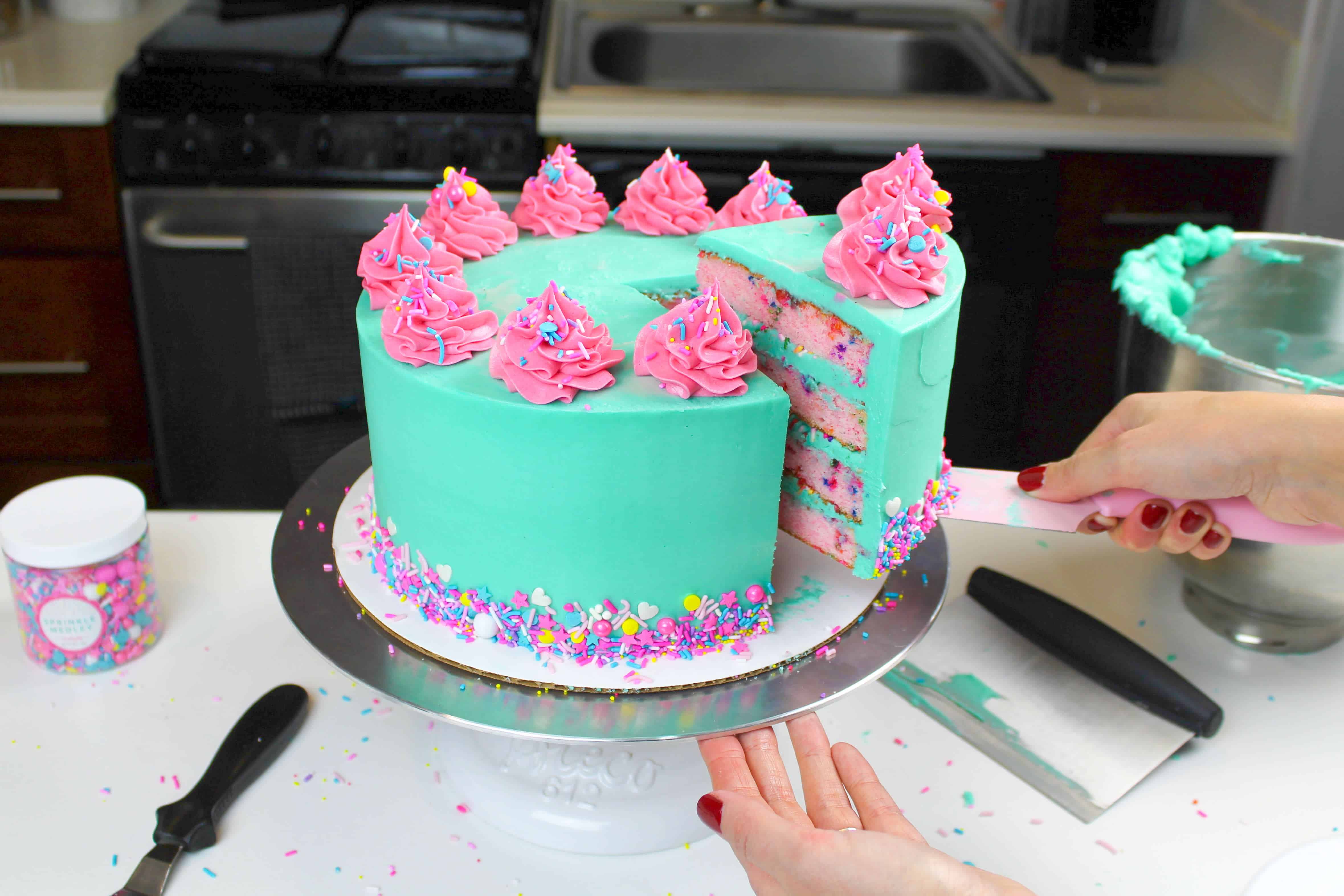 colorful funfetti cake, decorated with teal and pink buttercream and colorful sprinkles