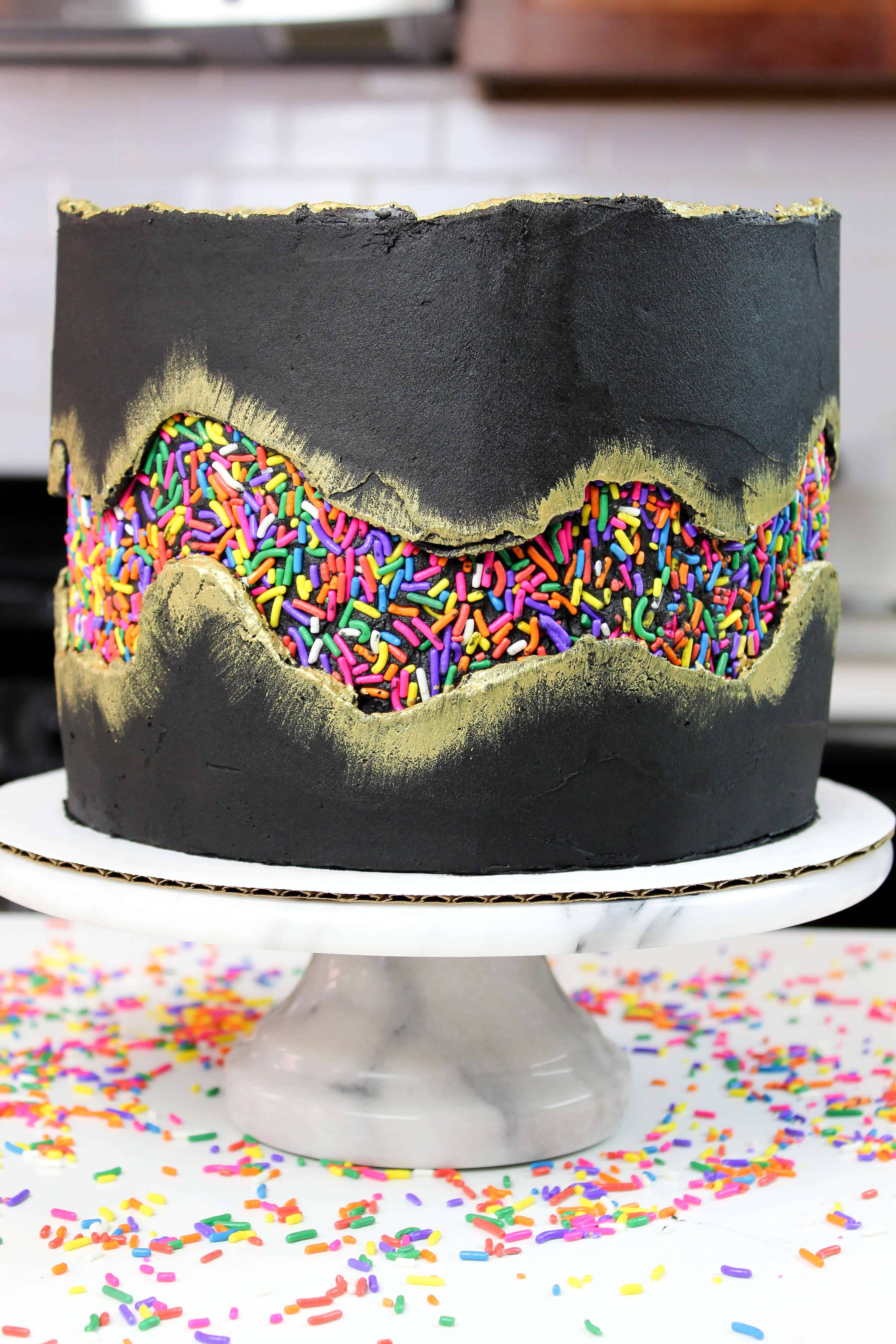 image of sprinkle fault line cake, frosted with black buttercream