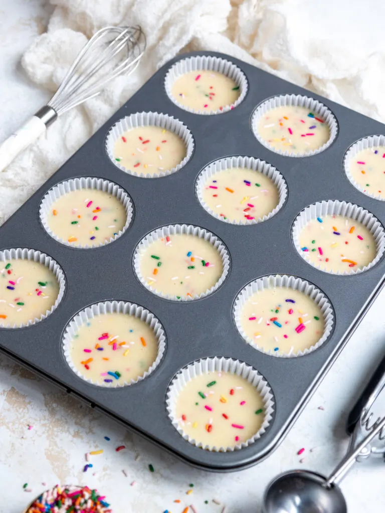 image of funfetti cupcake batter that's been poured into cupcake liners and are ready to be baked