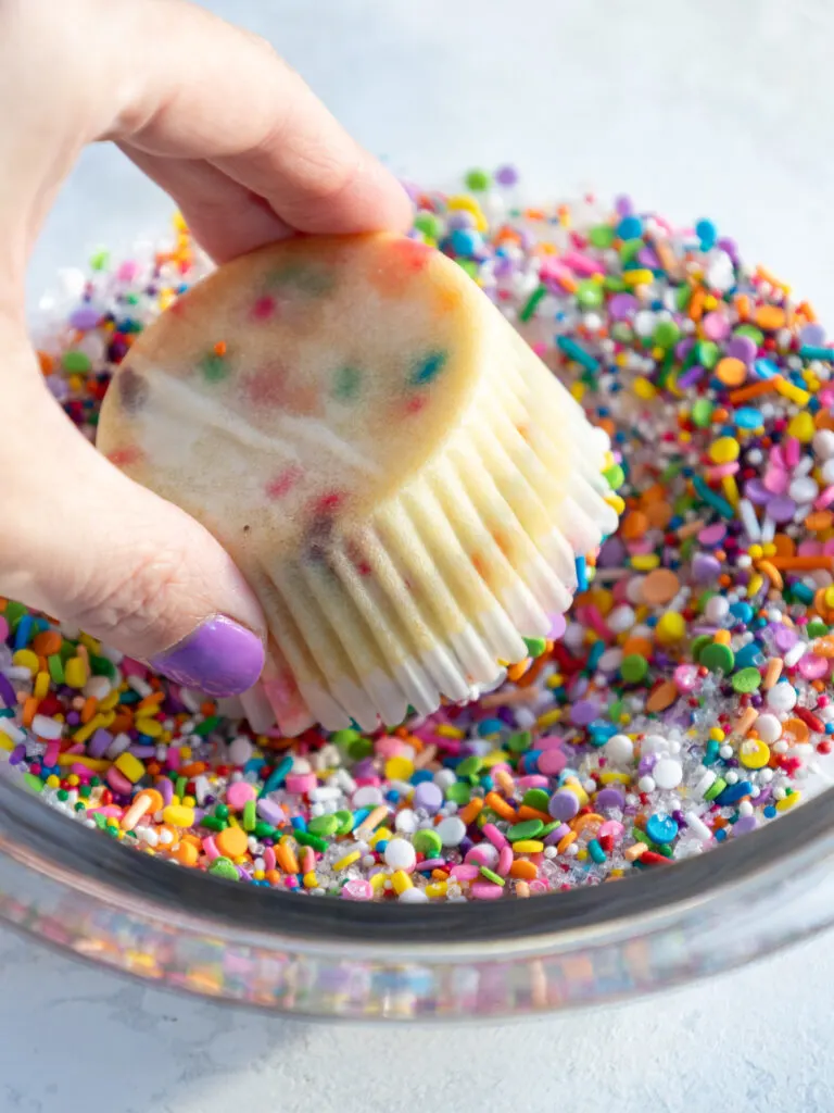 image of a funfetti cupcake being dunked into rainbow sprinkles