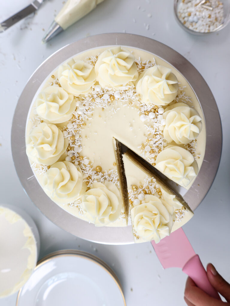 image of a WASC cake that's been frosted with almond buttercream and 
cut into and a slice is being pulled out