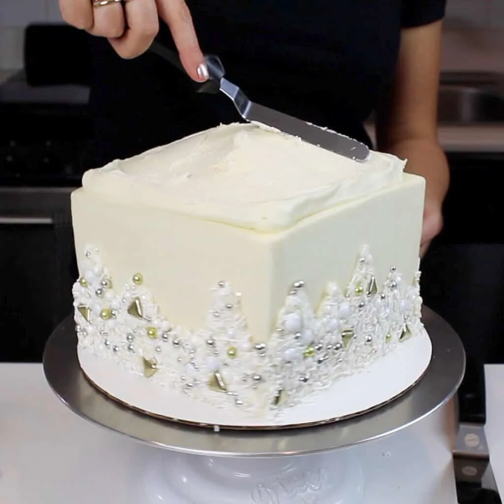 adding frosting on top of a cardboard cake round to put fresh flowers on a cake photo