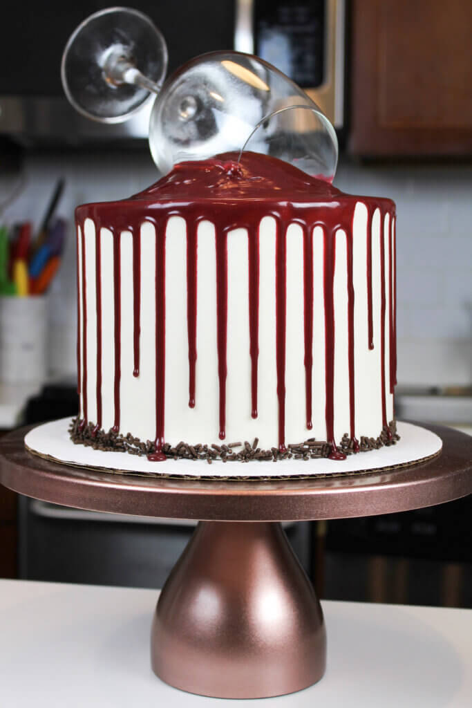 image of decorated red wine cake, with red wine drips and chocolate sprinkles around the base