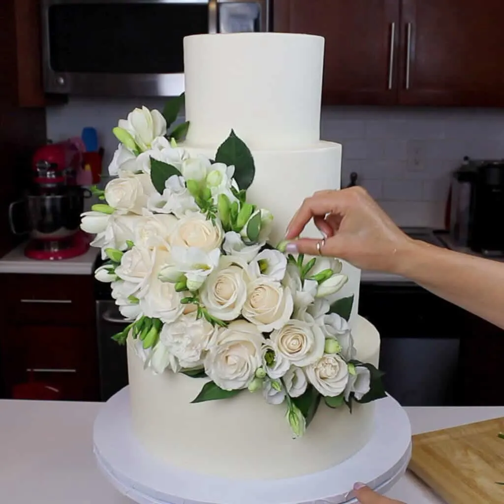 photo of 4 tier wedding cake decorated with fresh flowers