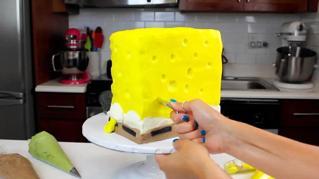 carving holes into spongebob cake with a small spoon