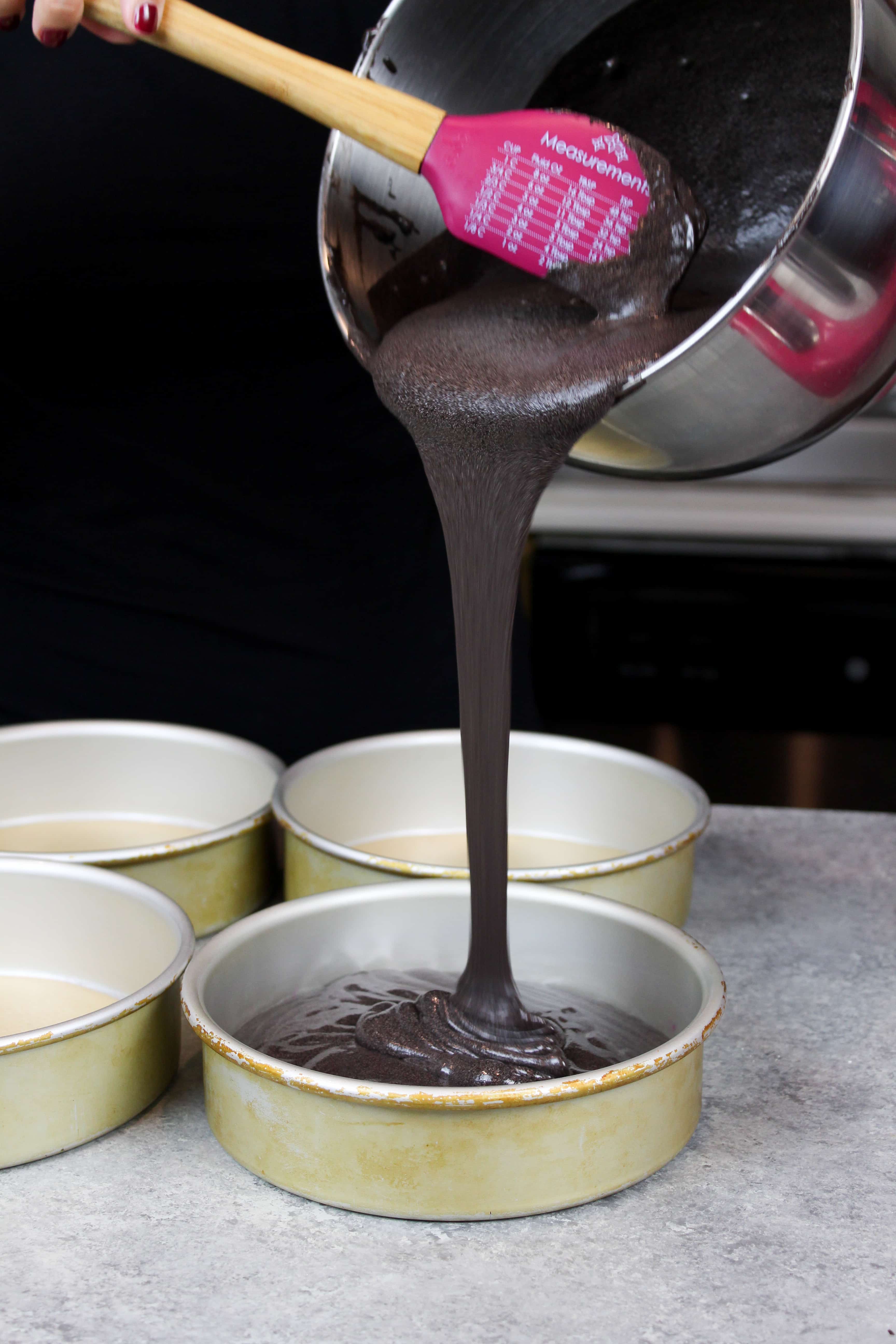  afbeelding van het gieten van zwart fluwelen cake beslag in pannen