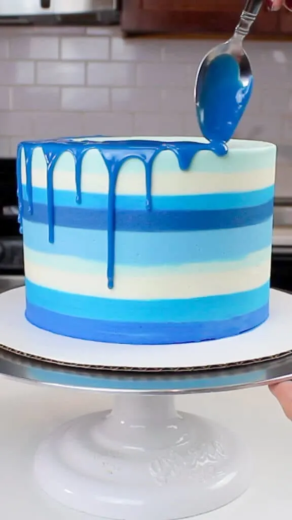 image of adding blue white chocolate ganache drips to the side of the cake
