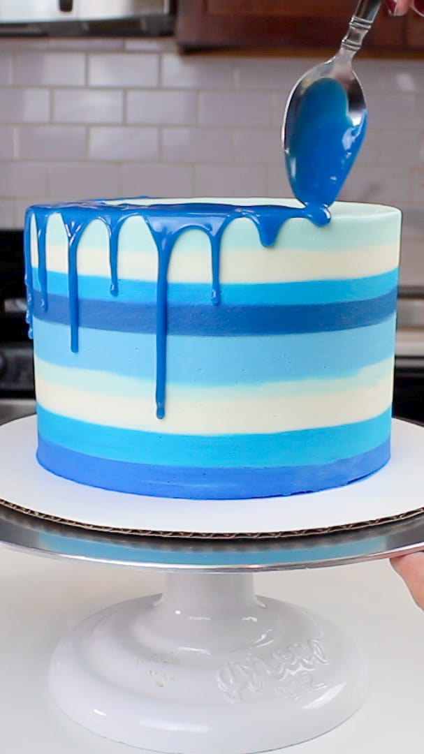 image of a blue colored drip being added to a striped blue cake