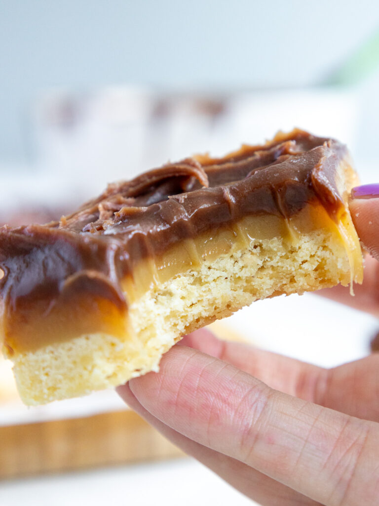 image of a millionaire bar that's been bitten into to show it's thick layers of caramel, chocolate ganache, and shortbread crust