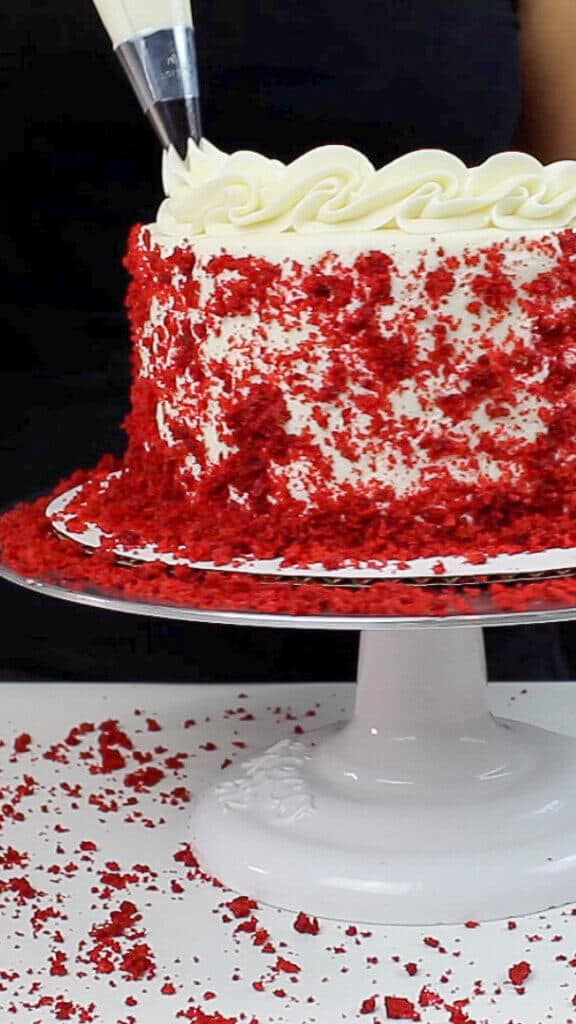 image of border being piped on red velvet layer cake