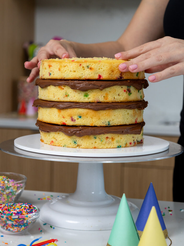 image of yellow cake layers being stacked and filled with chocolate buttercream