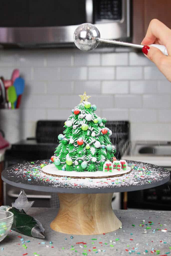 image of small christmas tree cake being dusted with powdered sugar