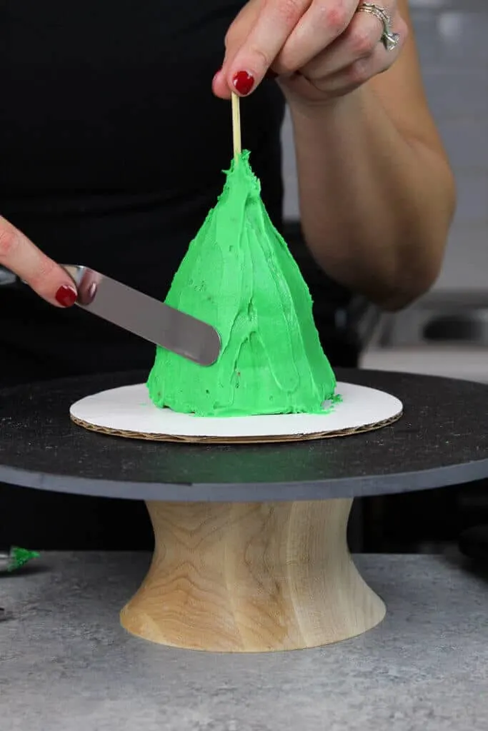 image of crumb coat being added to stacked cupcakes to make a mini christmas tree