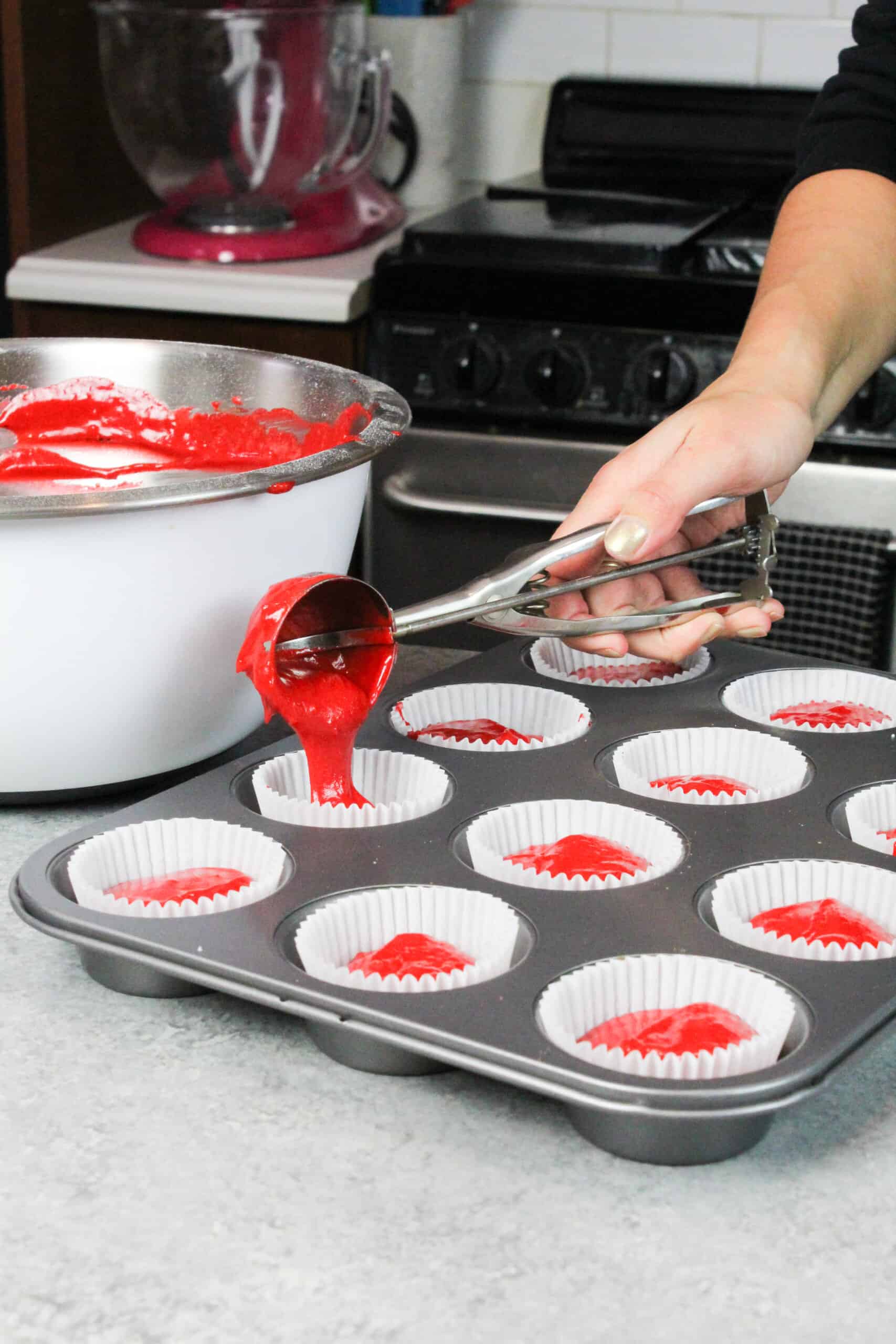 image of scooping red velvet cupcake batter into cupcake liners