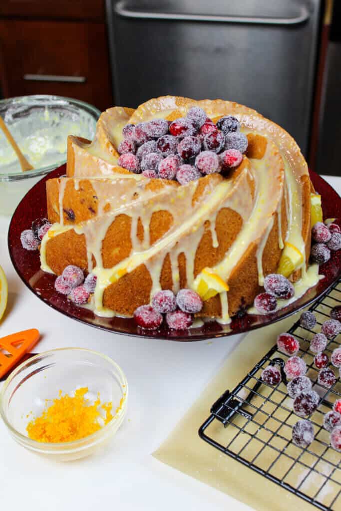 image of orange and cranberry bundt cake decorated with orange glaze and sugared cranberries