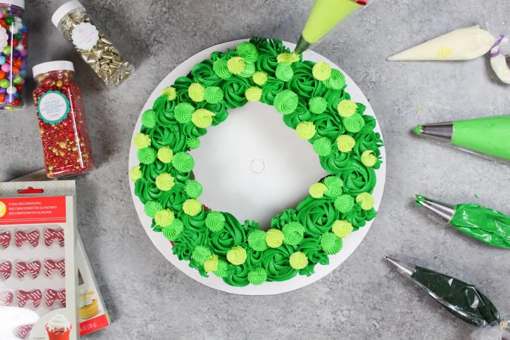 image of piping green buttercream frosting onto wreath cucpakes