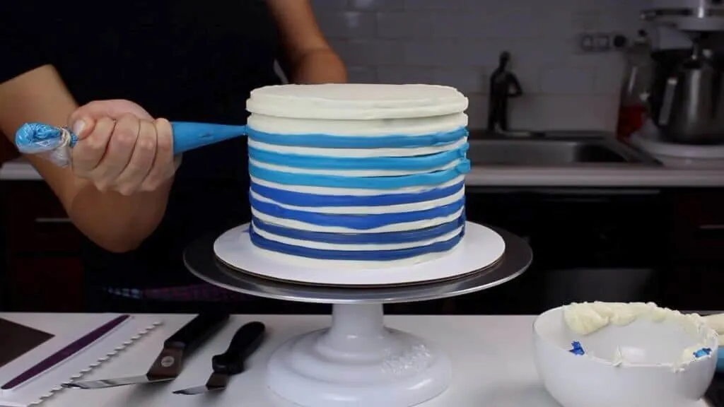 image of colorful frosting being piped onto buttercream cake