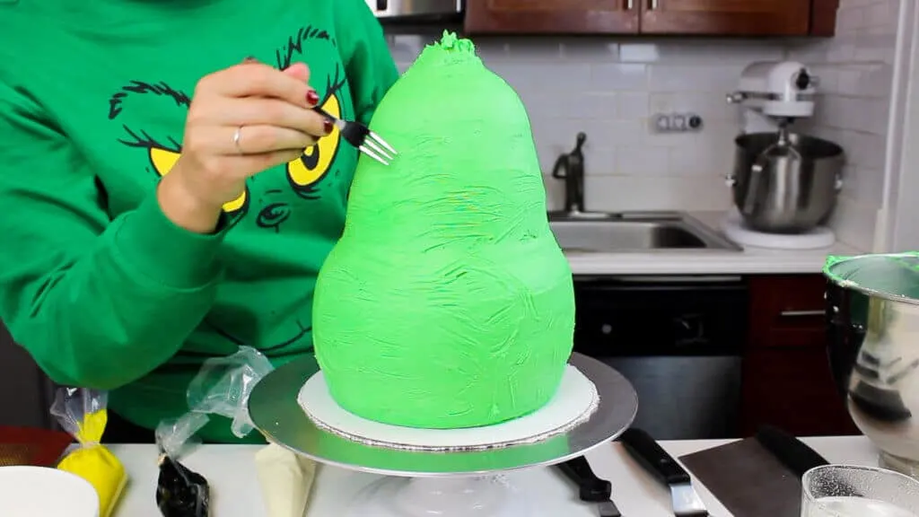 image of using a small fork to add a textured look to a grinch cake