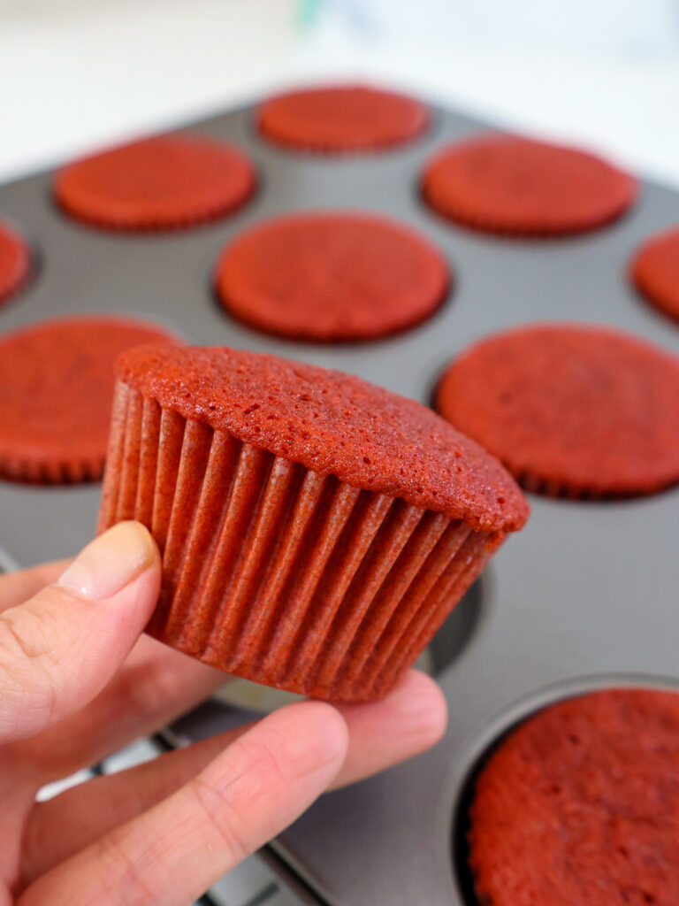 image of a red velvet cupcake being held up to show how nicely it baked up