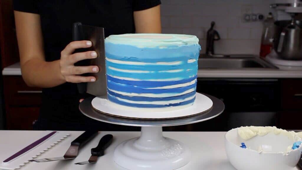 image of smoothing buttercream stripes on a cake
