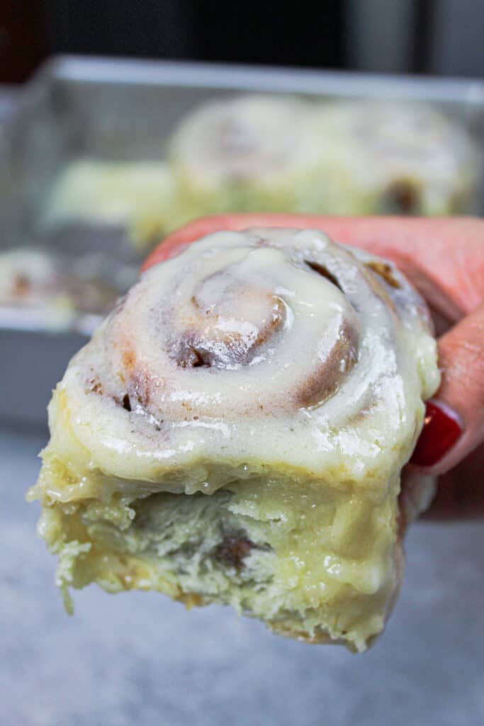 image of quick yeast cinnamon roll, held in hand to show how fluffy and soft it is