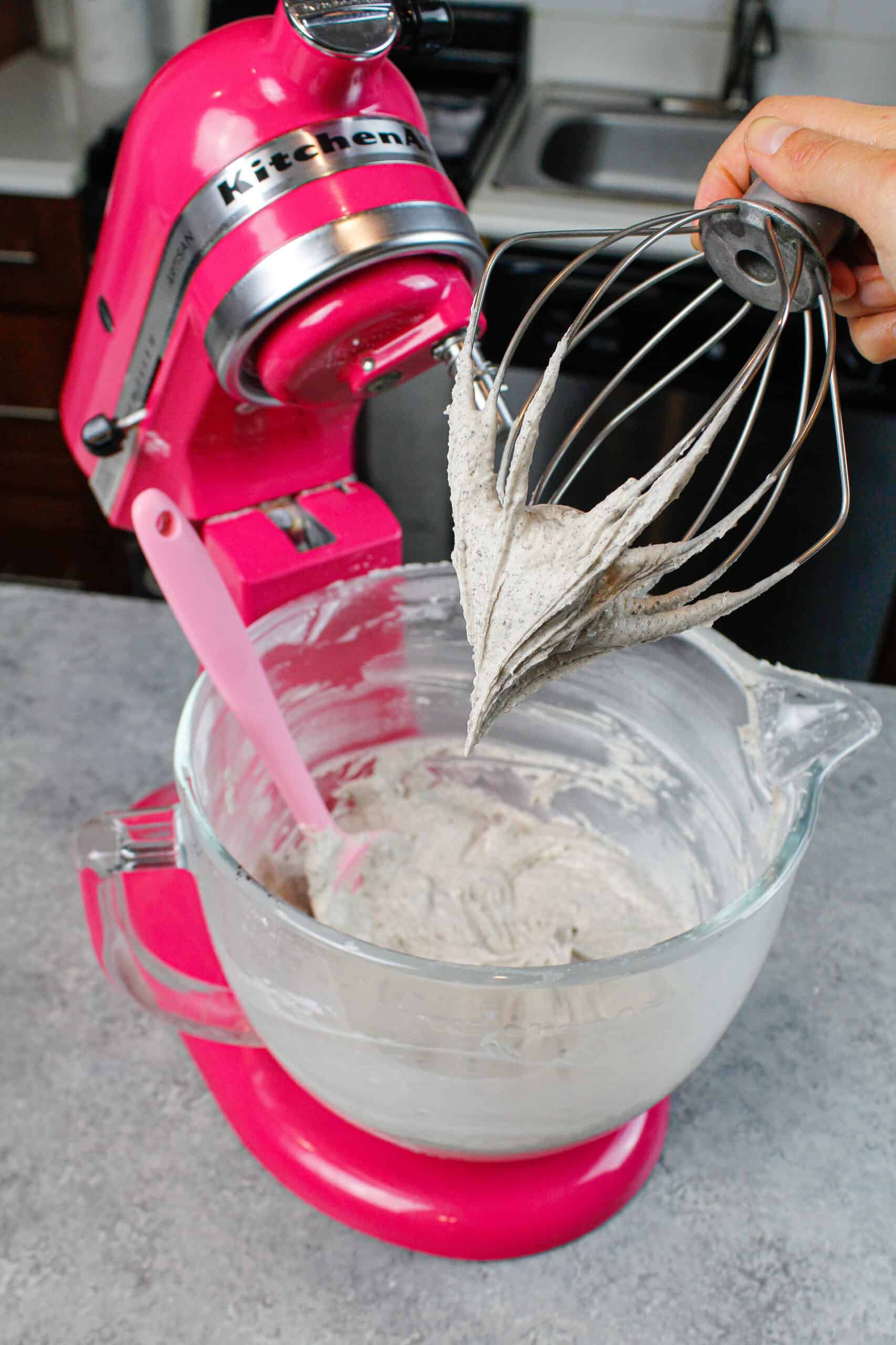 image of oreo frosting on a whisk attachment, after just being made in a pink stand mixer