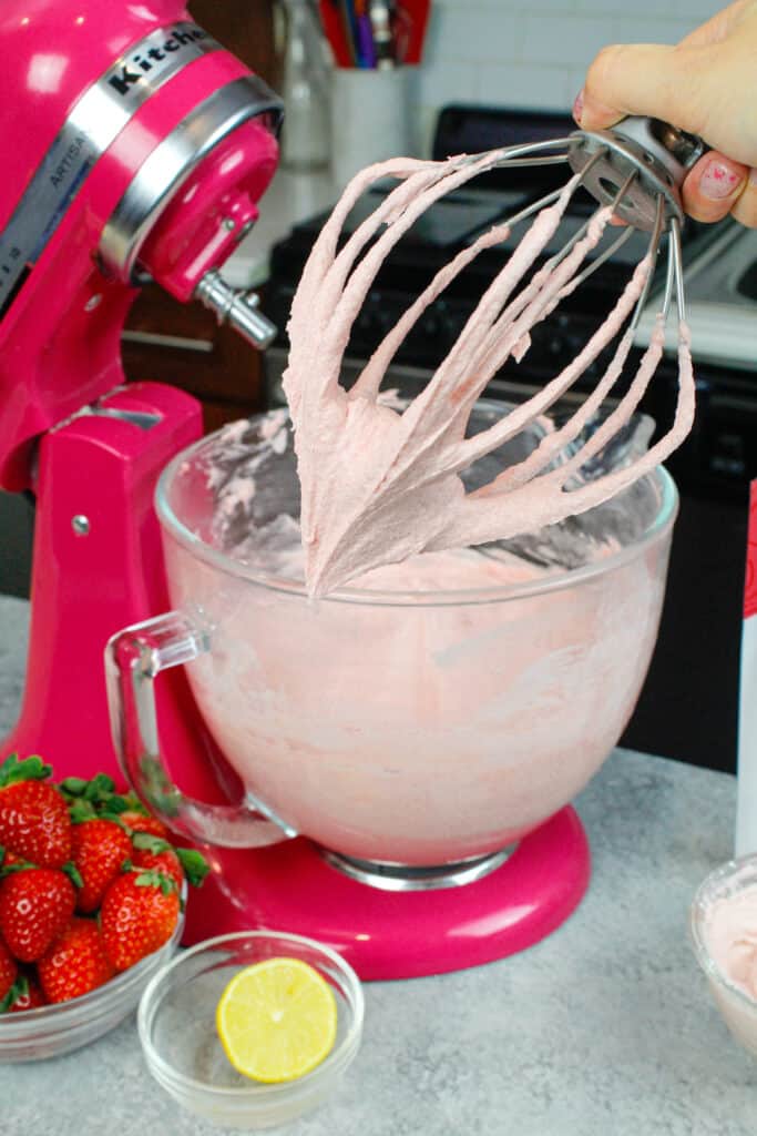 image of strawberry buttercream on whisk attachment with kitchenaid mixer in the background