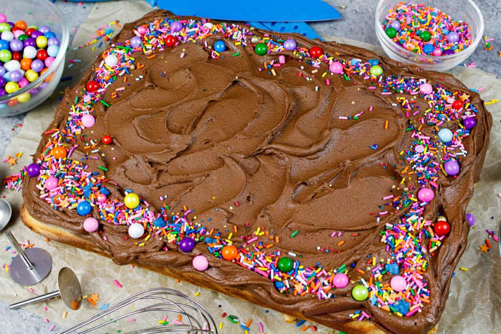 image of yellow sheet cake decorated with chocolate buttercream and rainbow sprinkles