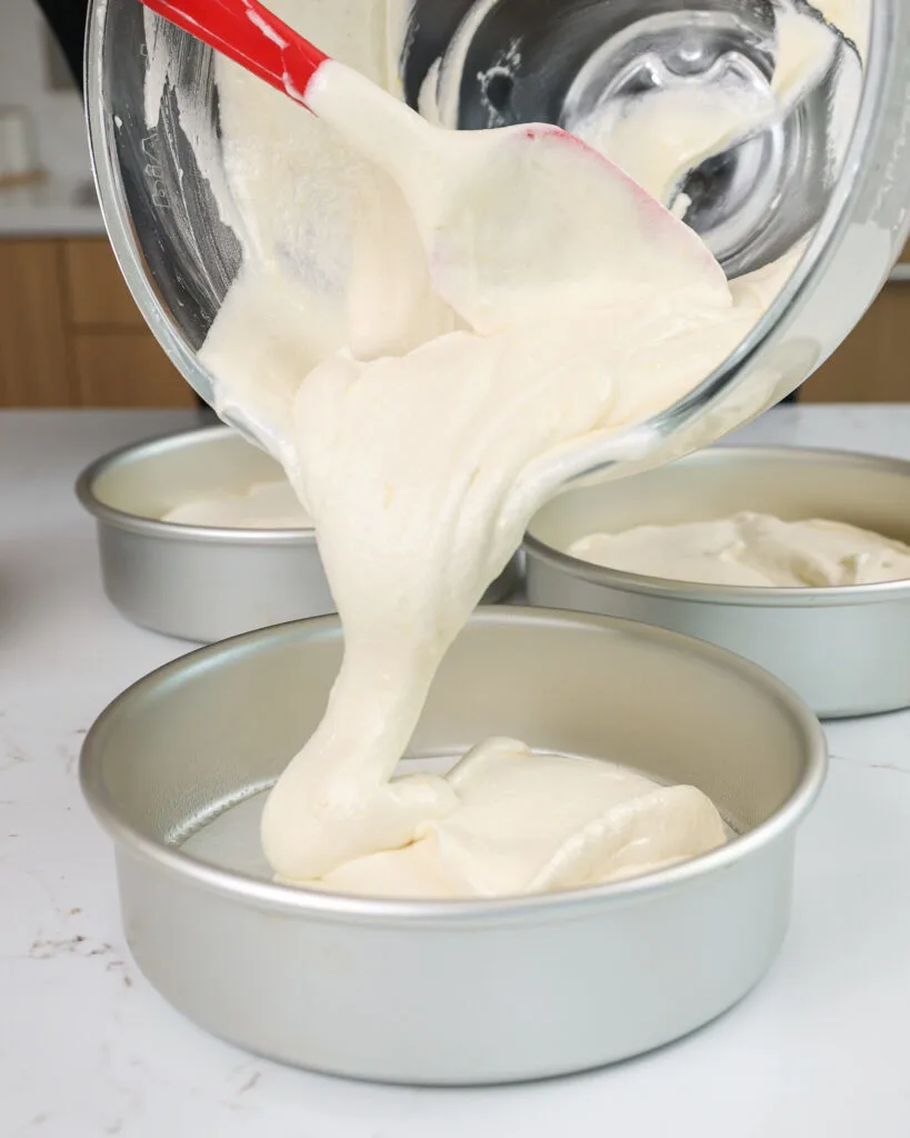 image of an 8 inch cake pan being filled with fluffy white cake batter to make a white chocolate raspberry cake