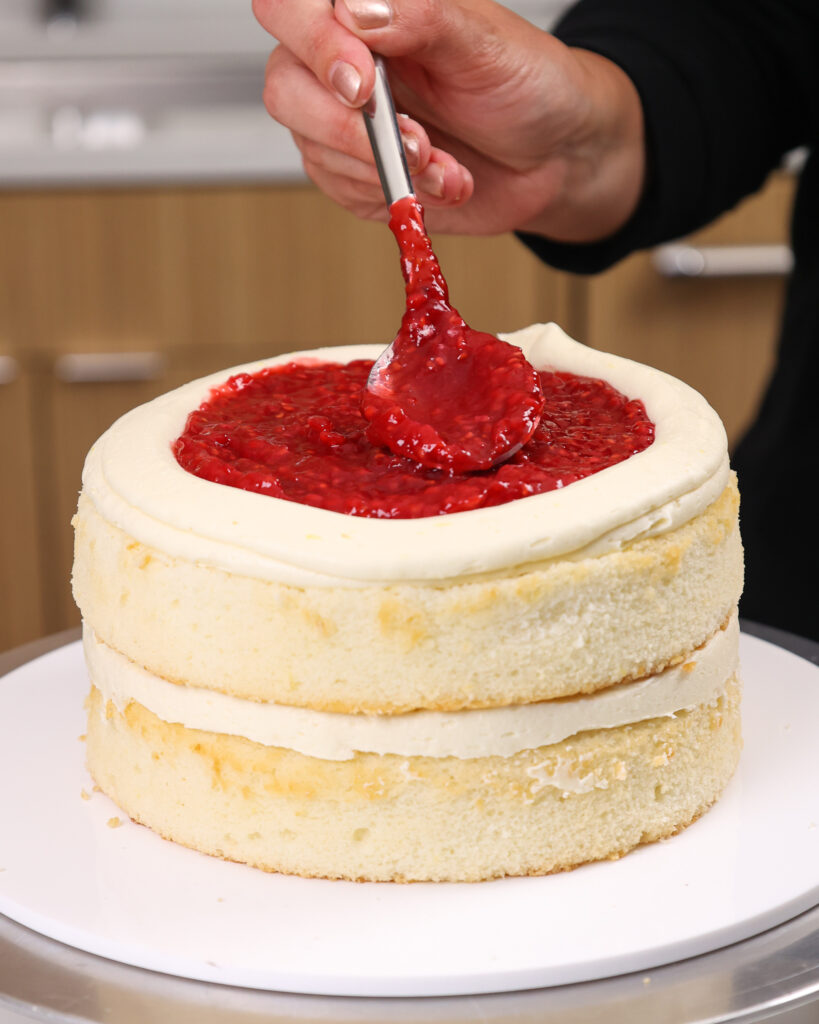 image of a white chocolate raspberry cake being filled with raspberry cake filling