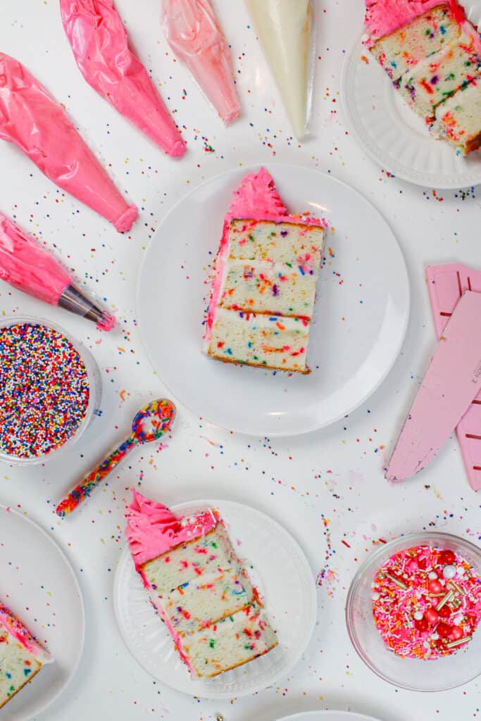  bilde av funfetti kake skiver, kuttet og omgitt av rosa frosting og regnbue sprinkles