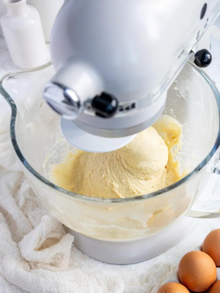 image of cinnamon roll dough being mixed in a stand mixer with a dough hook