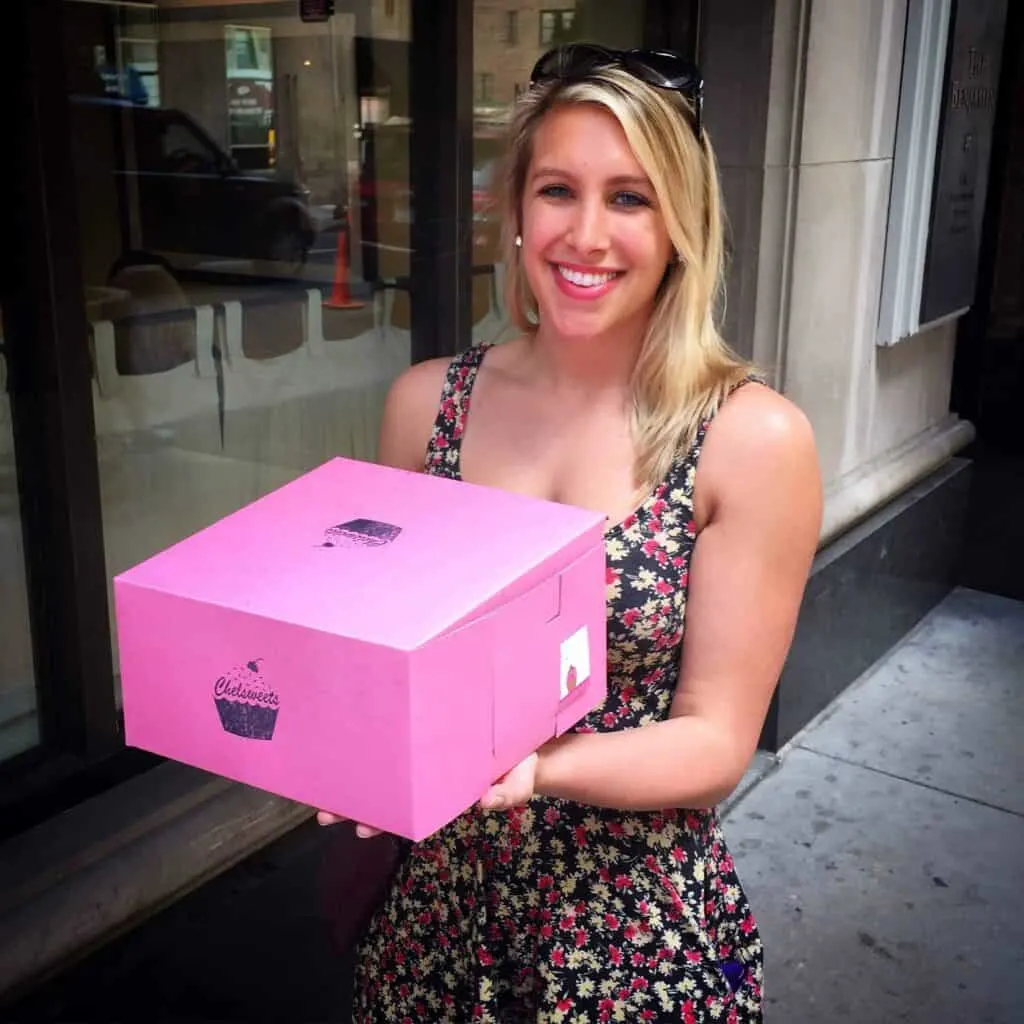 photo of chelsey white carrying a pink cake box
