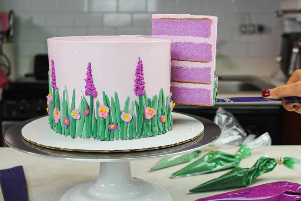 image of golden lavender cake cut with slice hovering in the air to show pretty and moist purple cake layers