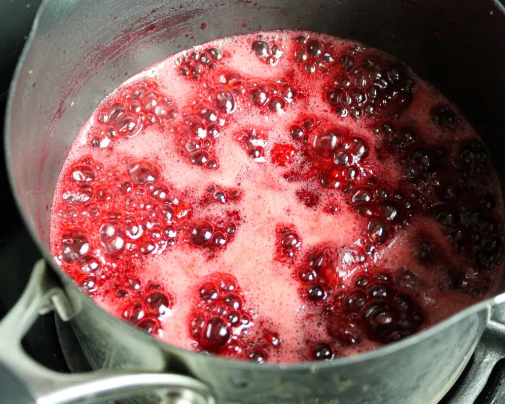 image of raspberry cake filling that's being cooked down in a saucepan