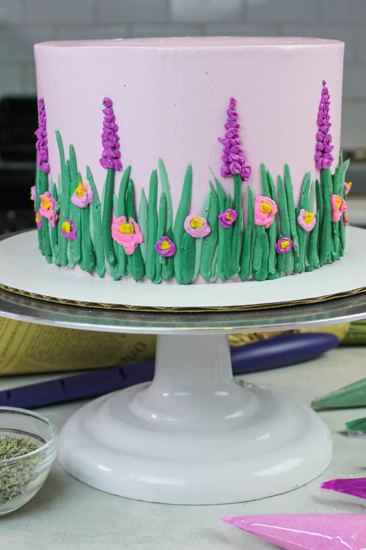 image of lavender layer cake decorated with lavender buttercream to look like a spring meadow