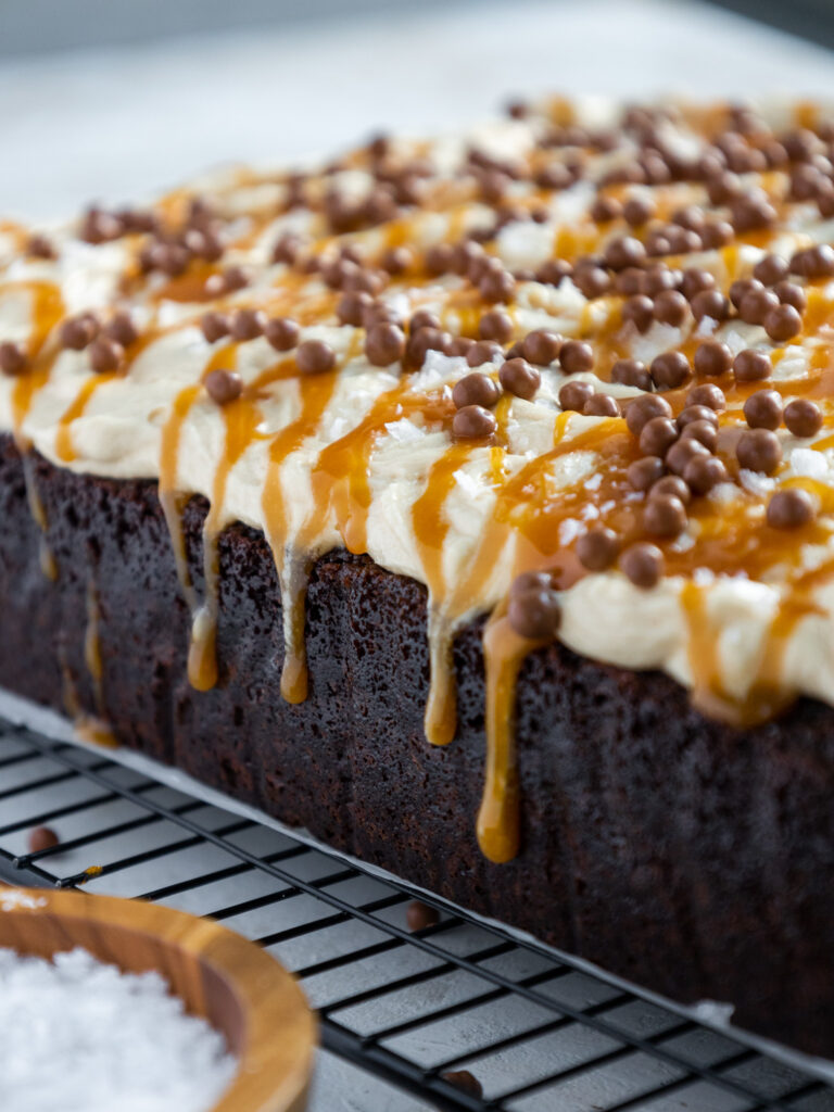 image of the side of a chocolate caramel poke cake that has caramel dripping down its sides
