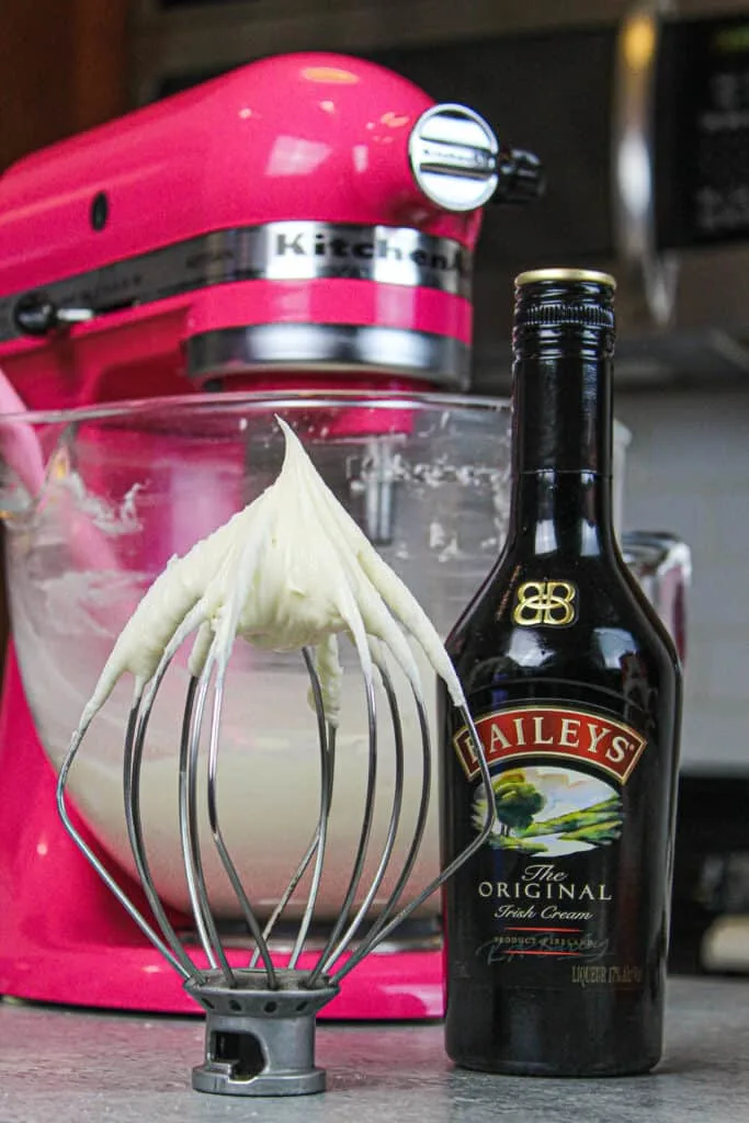 image of baileys frosting on whisk attachment resting on counter to show it's stiff enough to pipe with