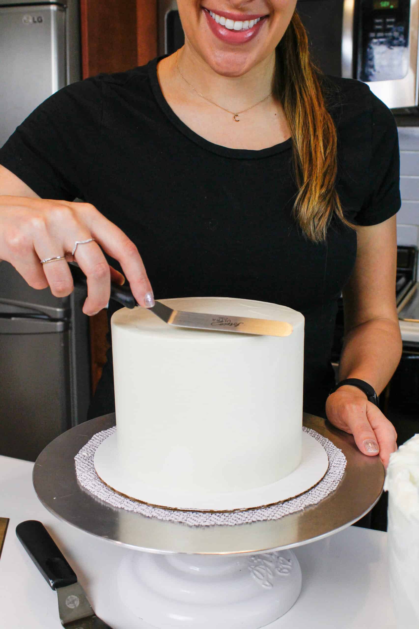 image of chelsey white of chelsweets smoothing frosting onto a cake