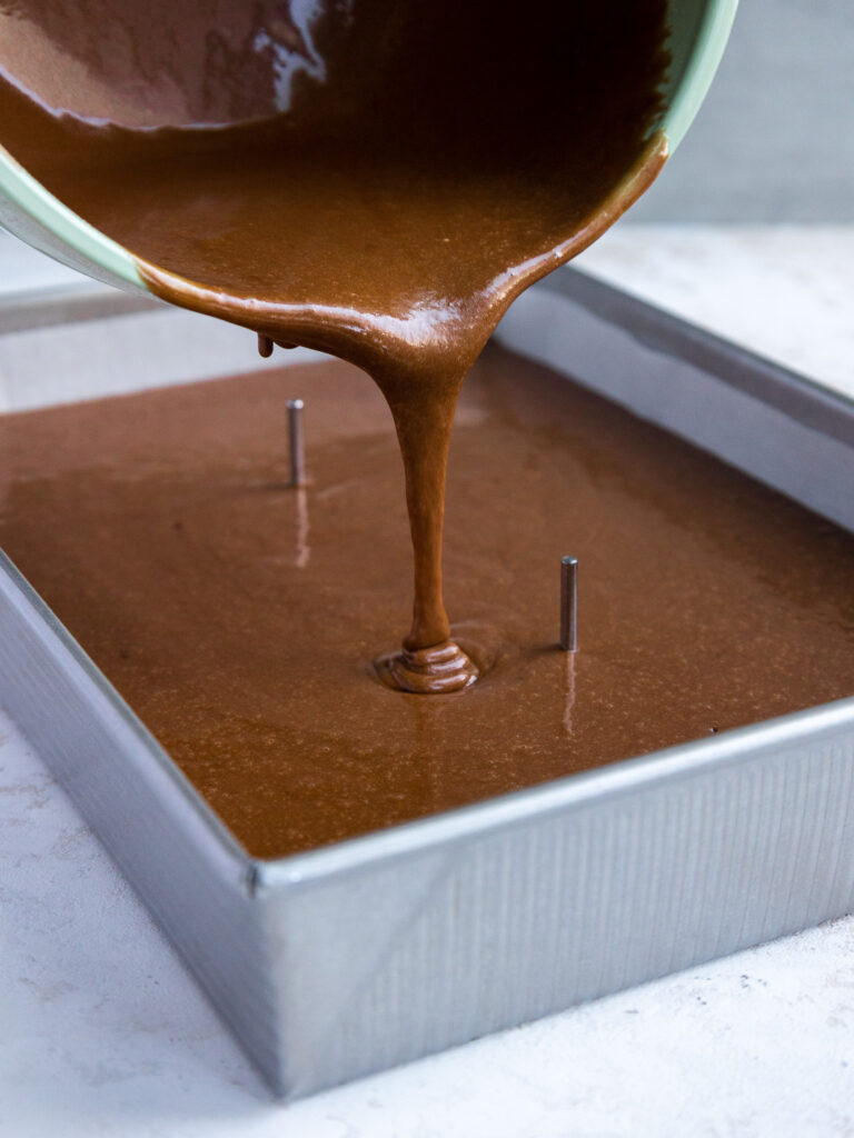 image of chocolate cake batter being poured into a quarter sheet cake pan