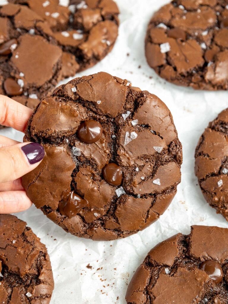 image of a baked brownie crinkle cookie being held up to show it's crinkly top 