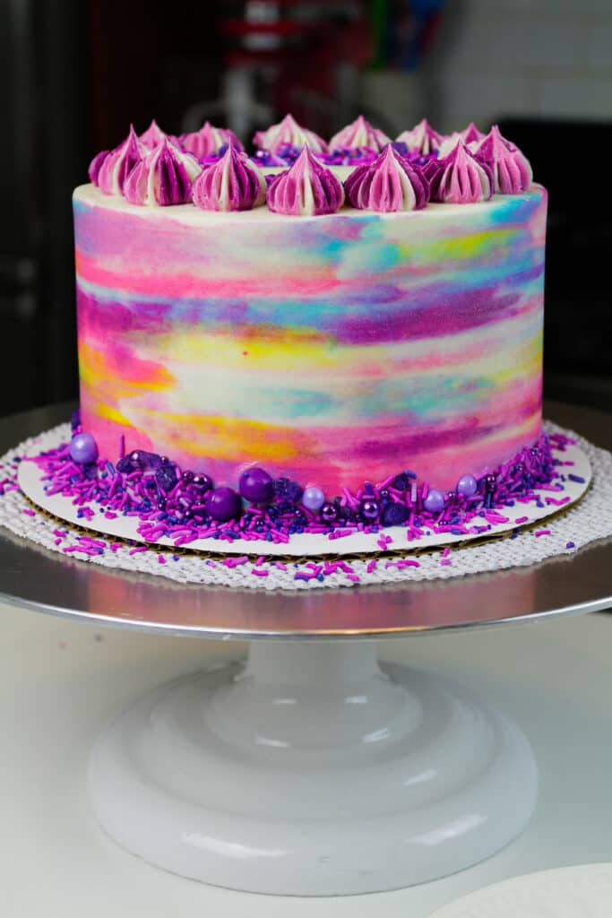 image of frosted vegan cake decorated to look like a watercolor painting with colorful frosting