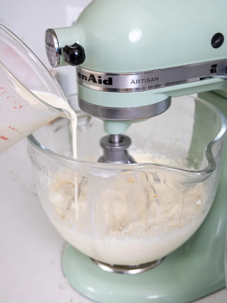 image of heavy cream being poured into a stand mixer to make stabilized whipped cream