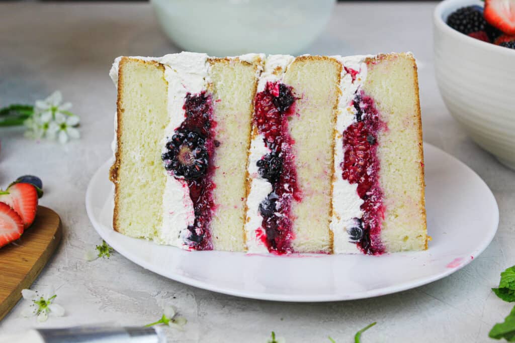 photo of a slice of berry chantilly cake showing mixed berry filling and fluffy mascarpone cream