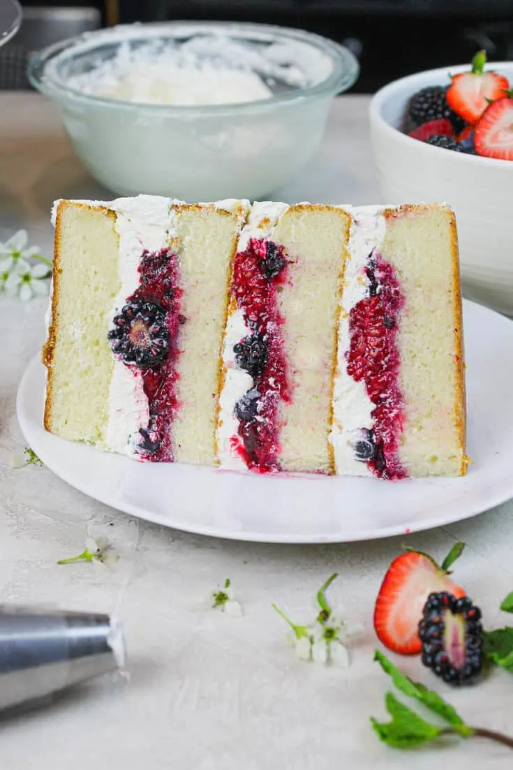 photo of a slice of berry chantilly cake showing mixed berry filling and fluffy mascarpone cream