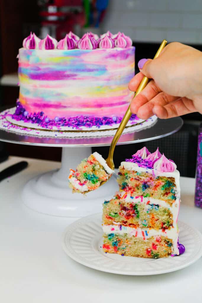 image of vegan funfetti cake with slice on plate and bite about to be taken with a fork