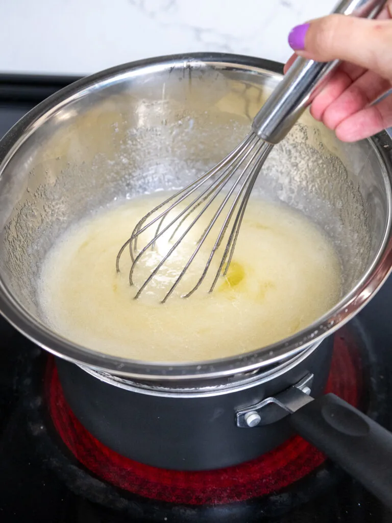 image of egg whites and sugar being whisked together over a double boiler to make Swiss meringue buttercream