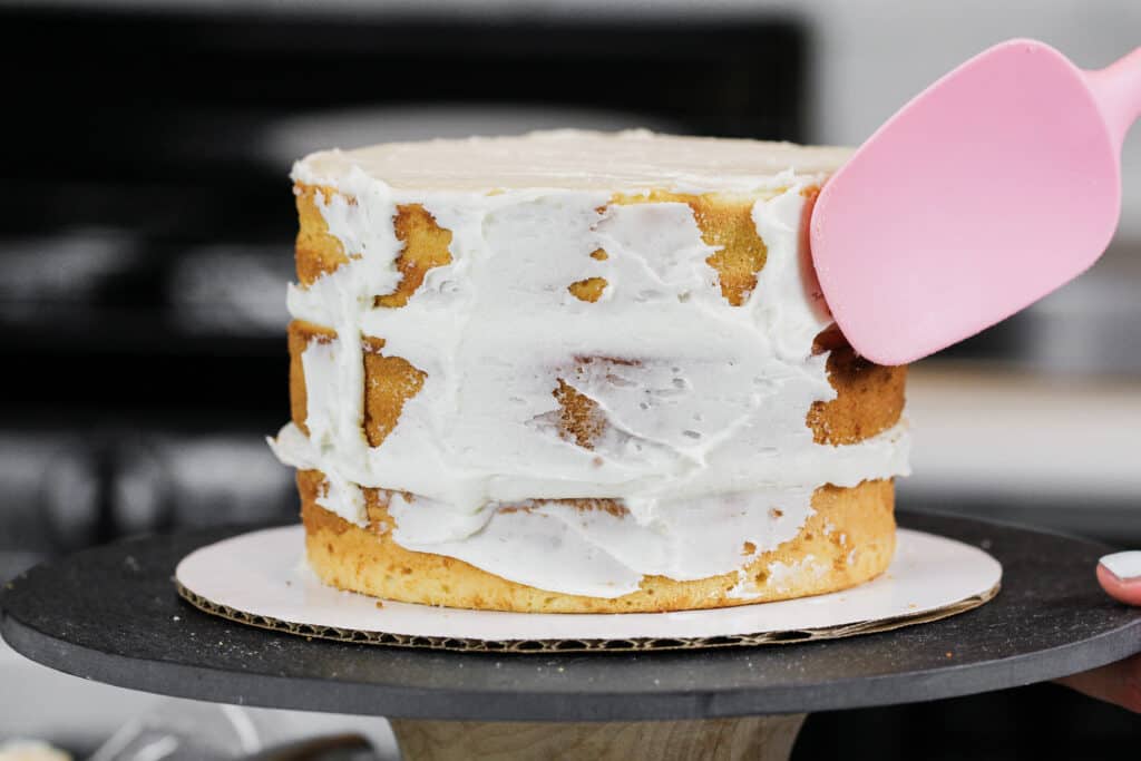 Image of a cake being frosted poorly with a rubber spatula